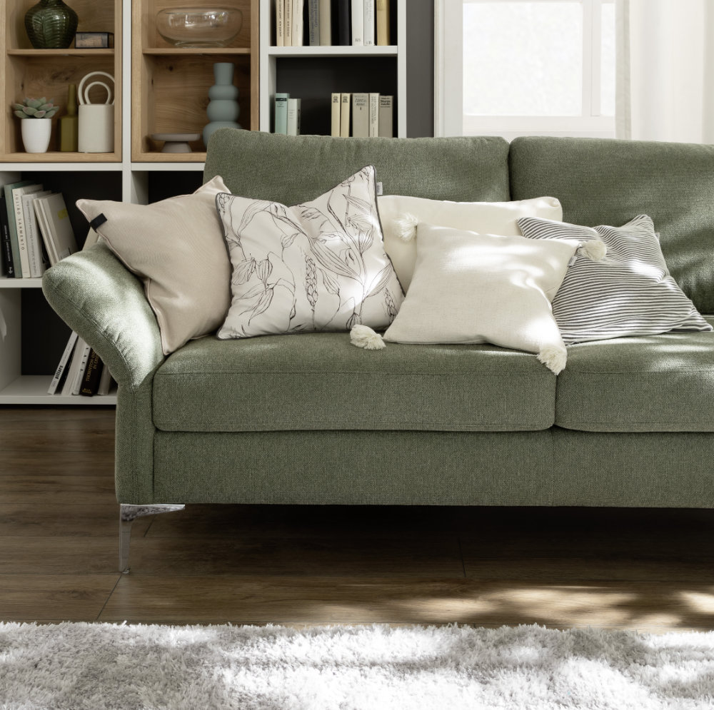 Helle Kissen auf grünem Sofa SCHOENER-WOHNEN-Textilien