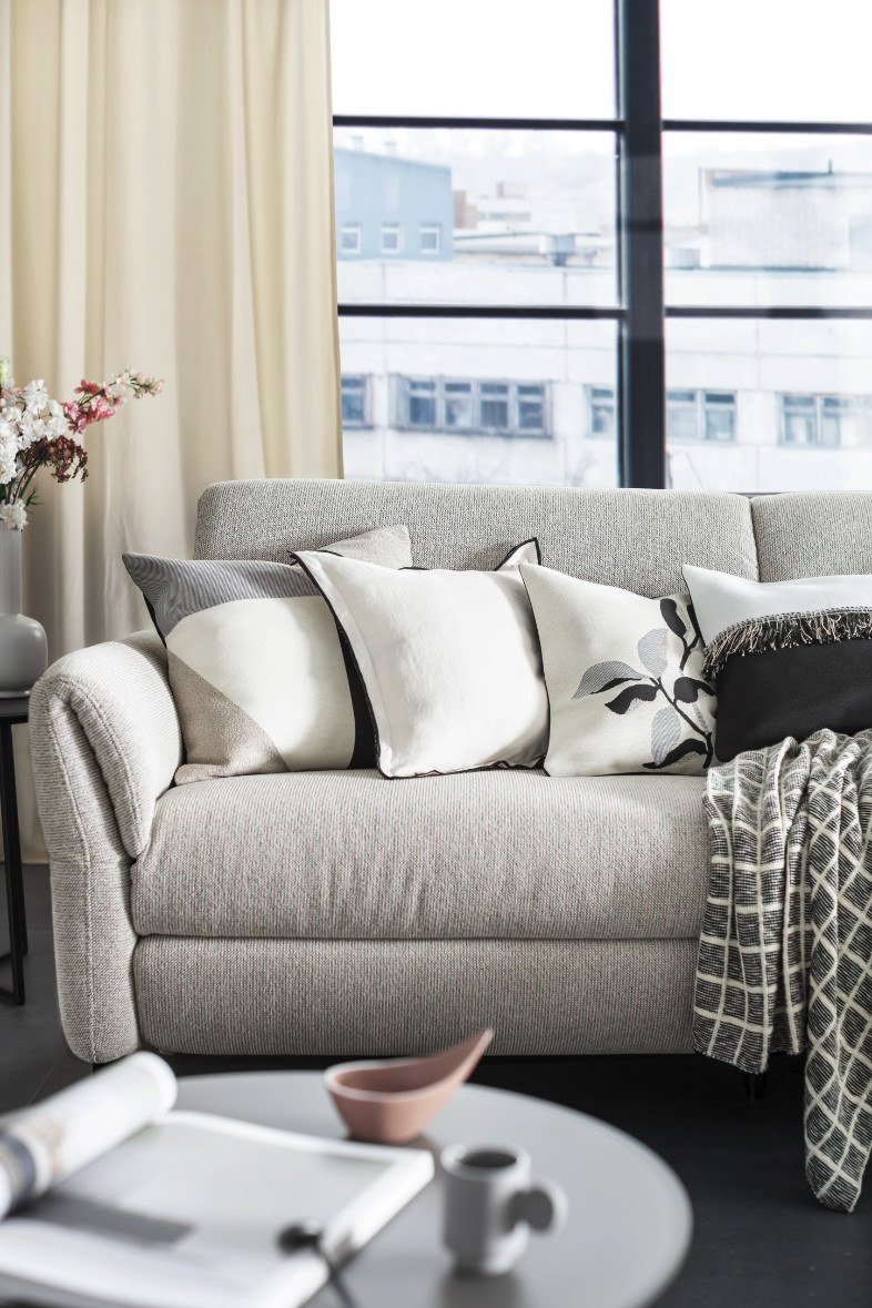 Wohnzimmer mit Sofa und gemütlichen Kissen und Decken SCHÖNER WOHNEN-Decken und Kissen