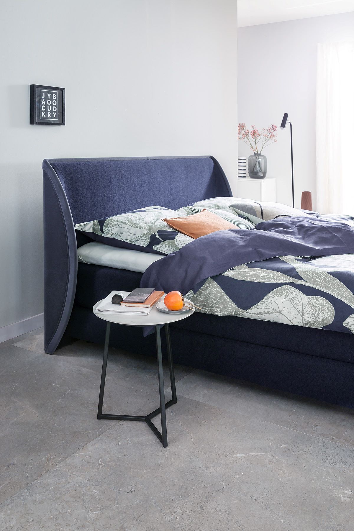 Schlafzimmer mit dunkelblauem Boxspringbett und Beistelltisch SCHÖNER WOHNEN-Schlafzimmer